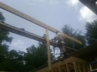 Carpenter setting a ridge beam over a new addition frame — Ice Dam Removal by Roofing Brothers in Donald