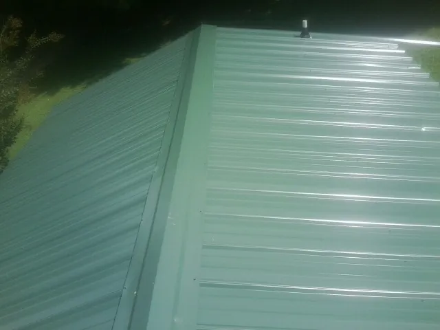 New green metal panels meeting at the ridge of a roof — Flat Roof Repair work by our crew in Donald