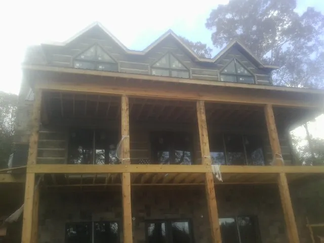 Dormers and porch framing on a large log home under construction — Roof Coating work by our crew in Donald