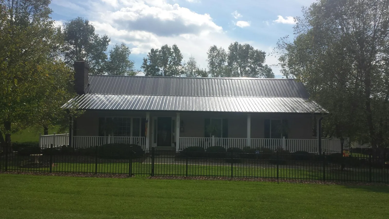 Gray metal roof on a brick ranch with a full width front porch — Gutter Guard Installation work by our crew in Donald