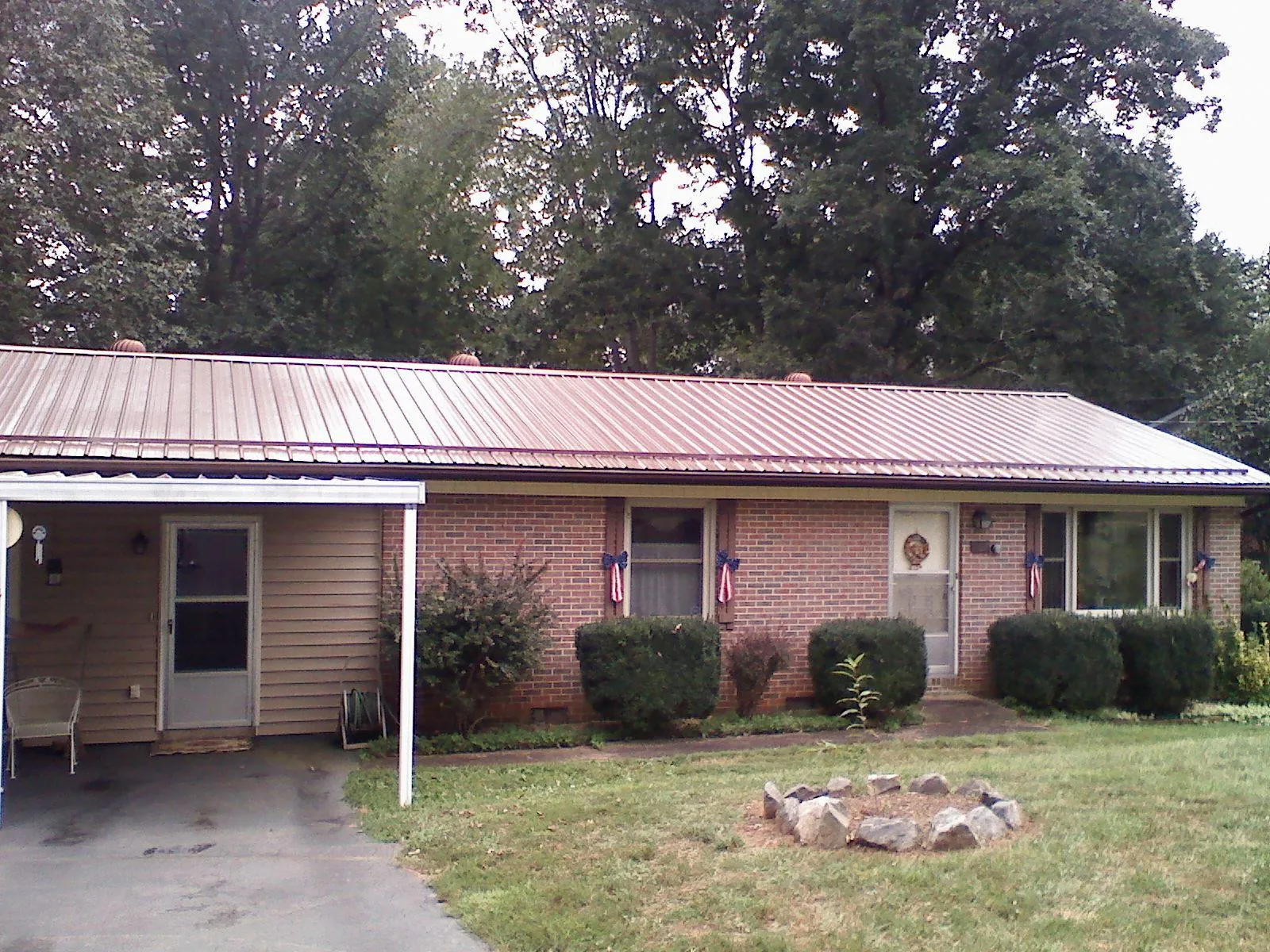 Bronze metal roof and carport on a brick ranch home — Roof Repair work by our crew in Donald